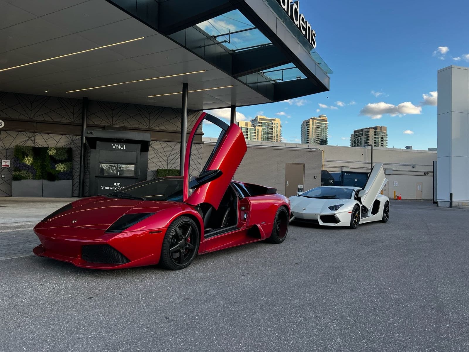 Red 2004 Murciélago with scissor door up beside a white Aventador roadster