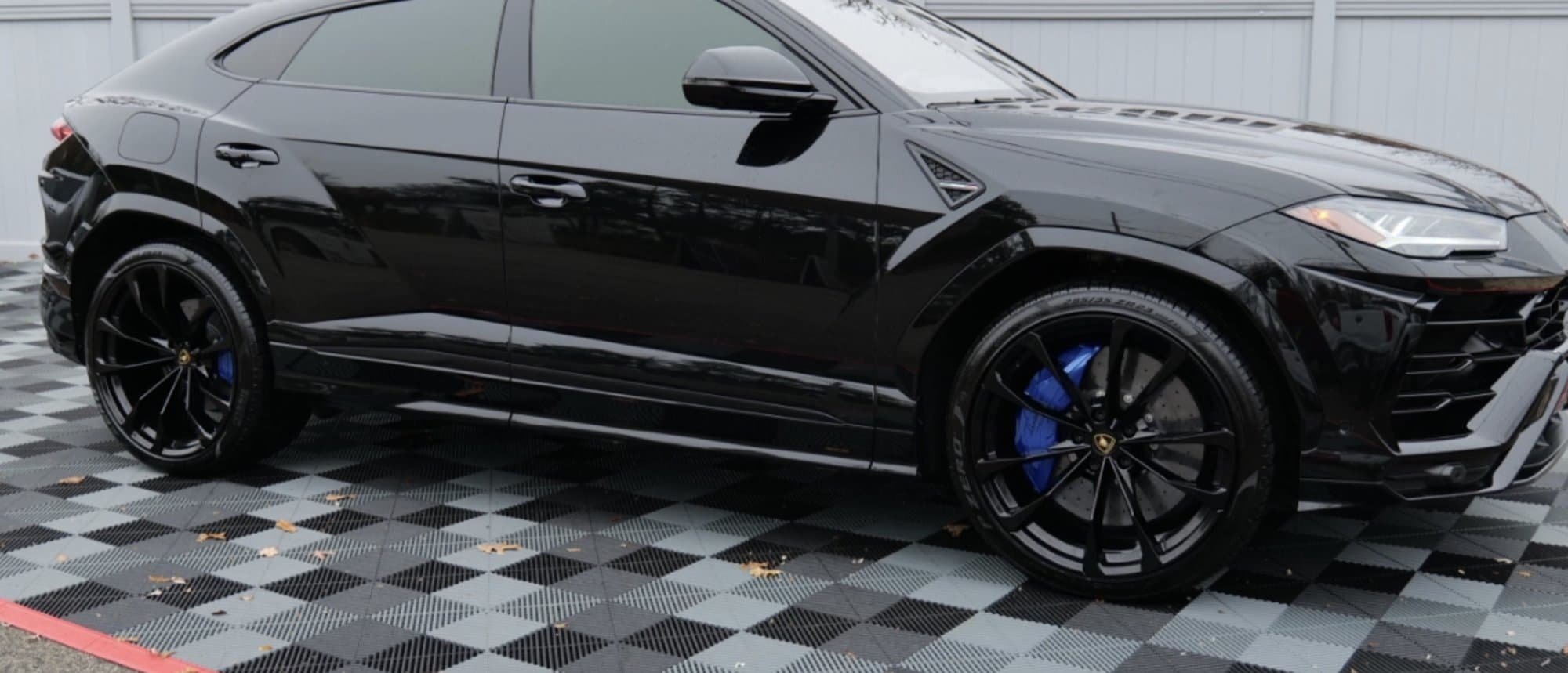 Side profile of the 2021 Lamborghini Urus on 23-inch gloss-black Taigete wheels with blue calipers