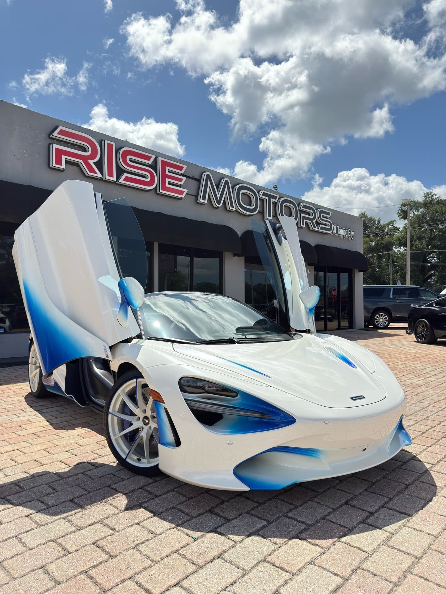 2021 McLaren 720S Spider in pearl white with a blue-fade finish, dihedral doors up — front three-quarter view, for sale from DDE Rentals