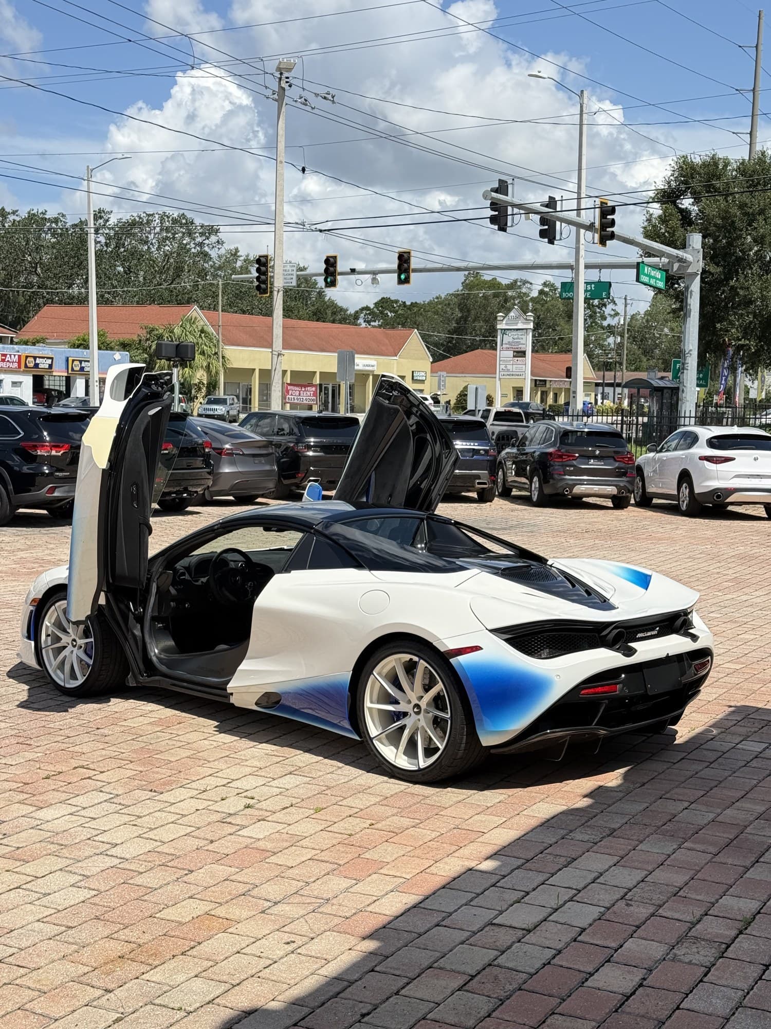 Rear three-quarter view of the 720S Spider with doors up, showing the blue-fade rear haunches and active rear wing