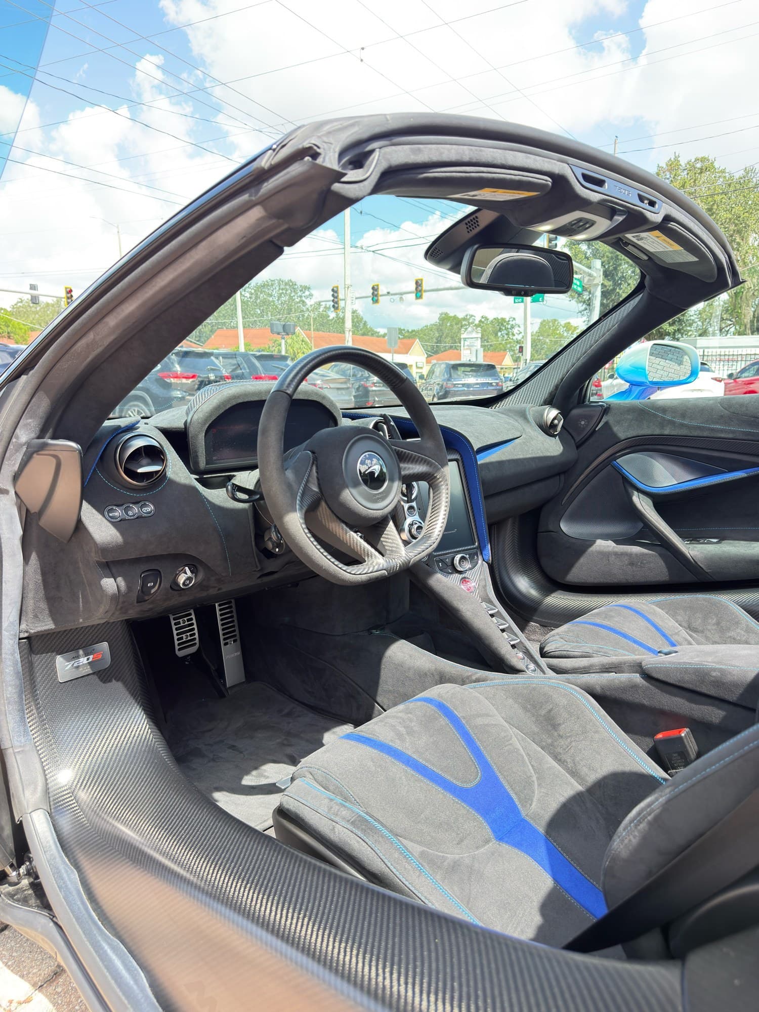 720S Spider cockpit — black Alcantara with blue accent stripes, carbon-fiber trim, roof open
